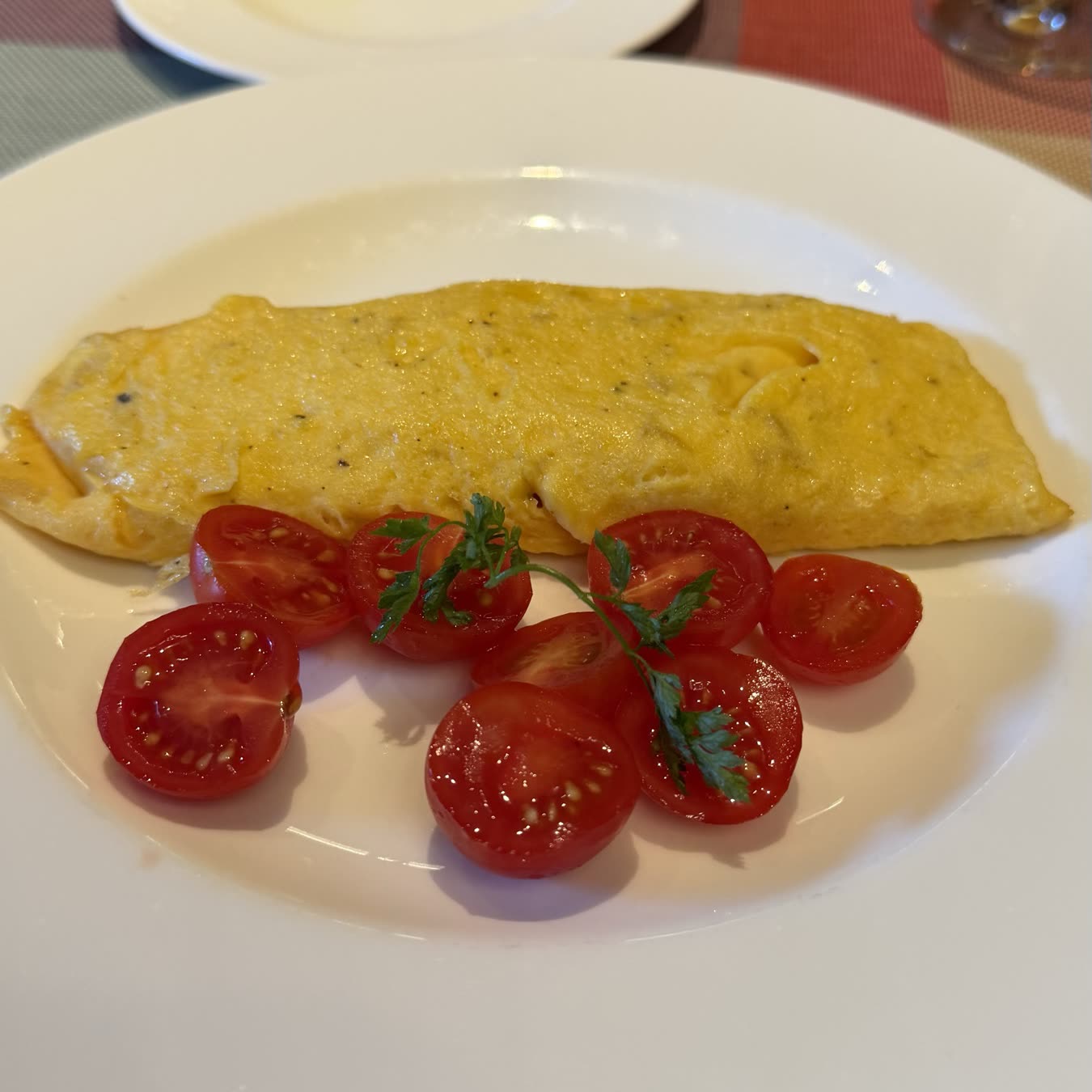 An omelette and halved cherry tomatoes on a white plate