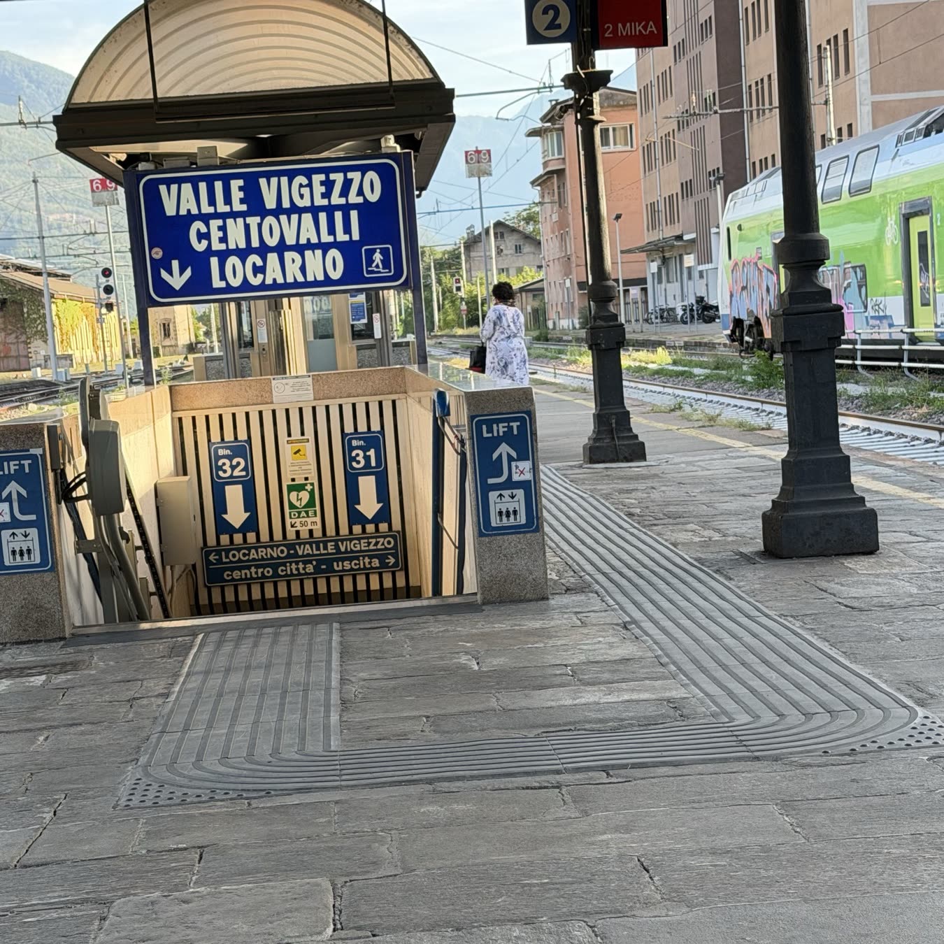 A station stairway with signs for platforms 31 and 32 and the Valle Vigezzo line to Locarno
