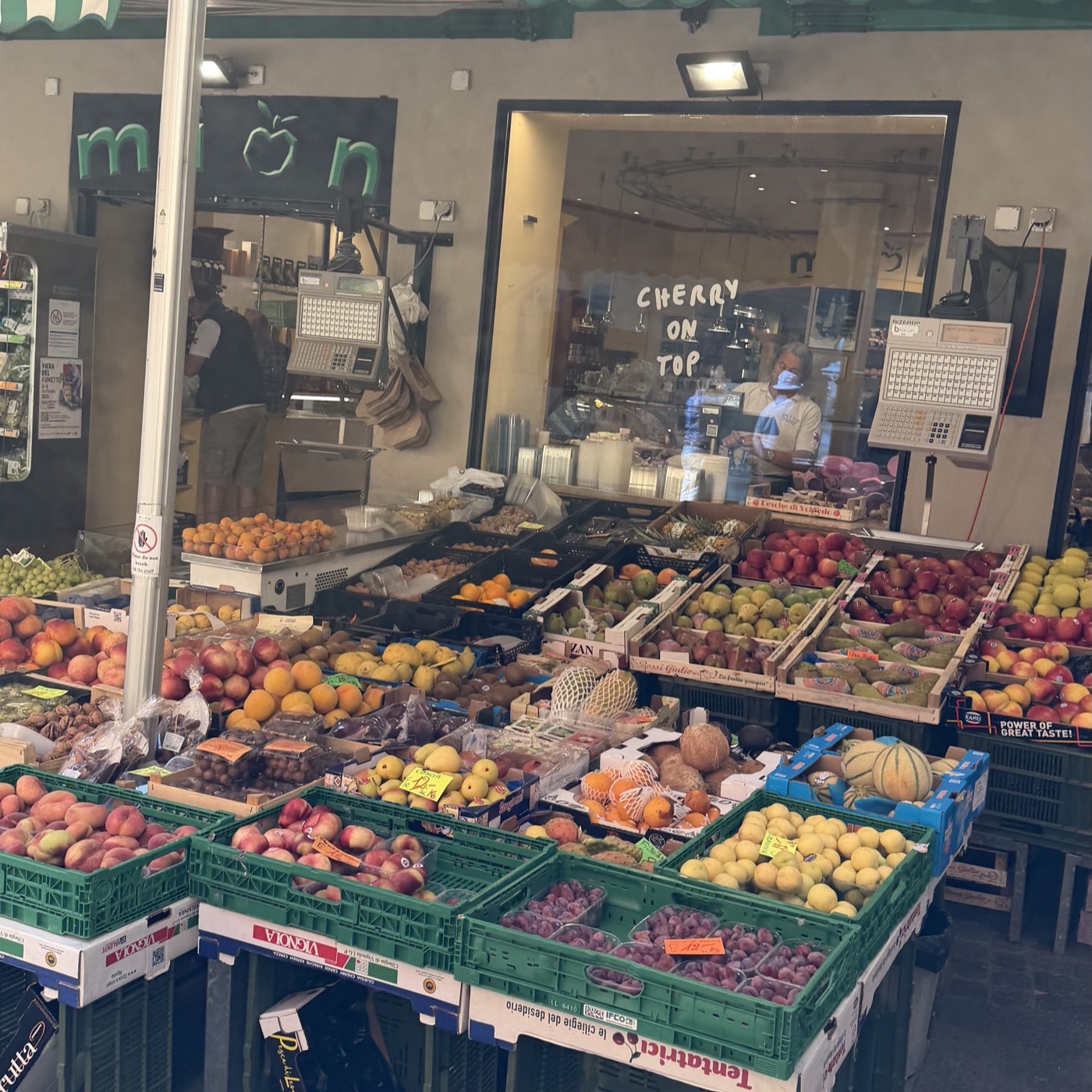 A fruit and vegetable stall under a green and white striped awning on a cobbled street
