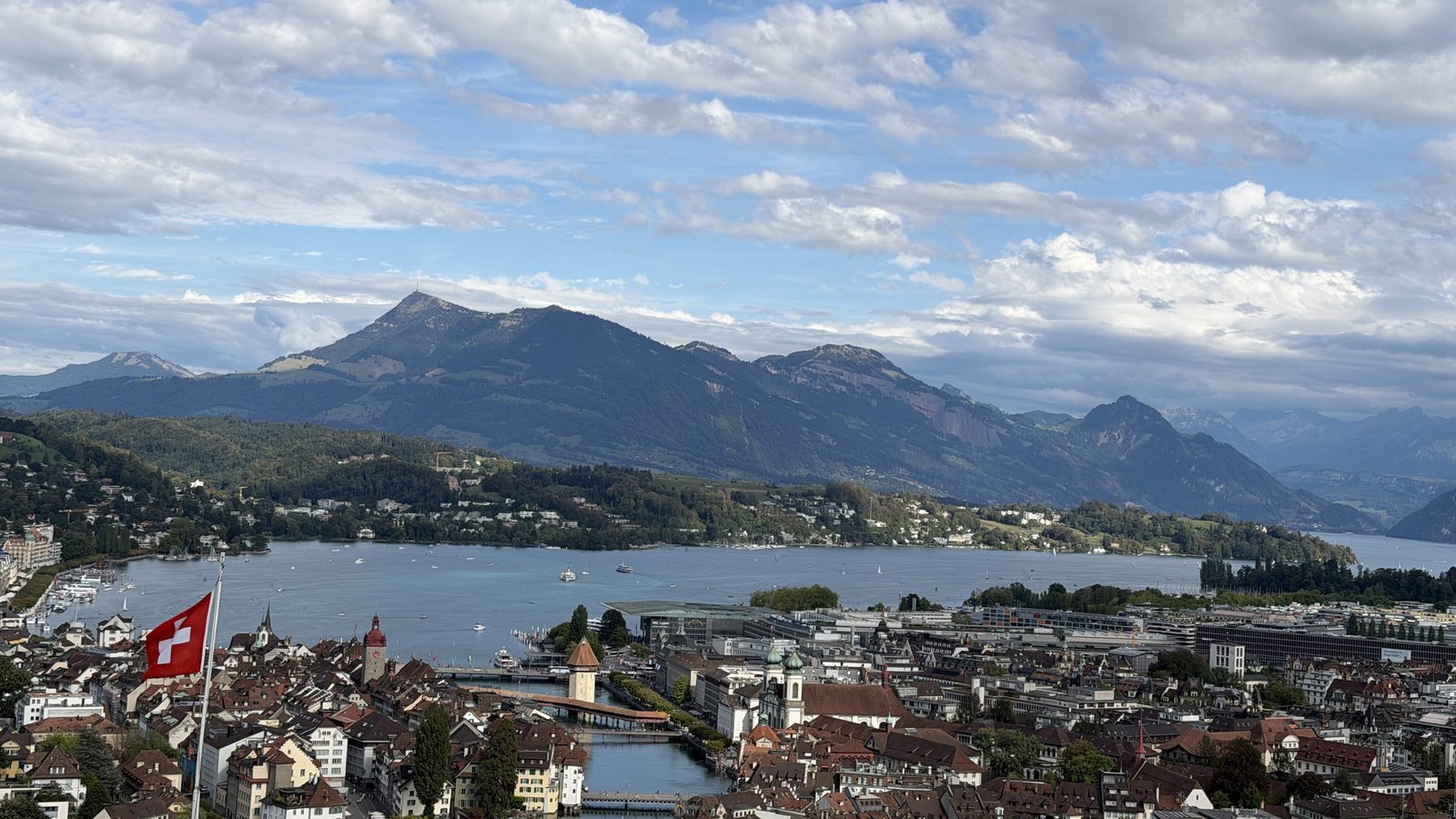 The view from the Château Gütsch terrace over the roofs of Lucerne to the lake and the mountains, with a Swiss flag in the foreground