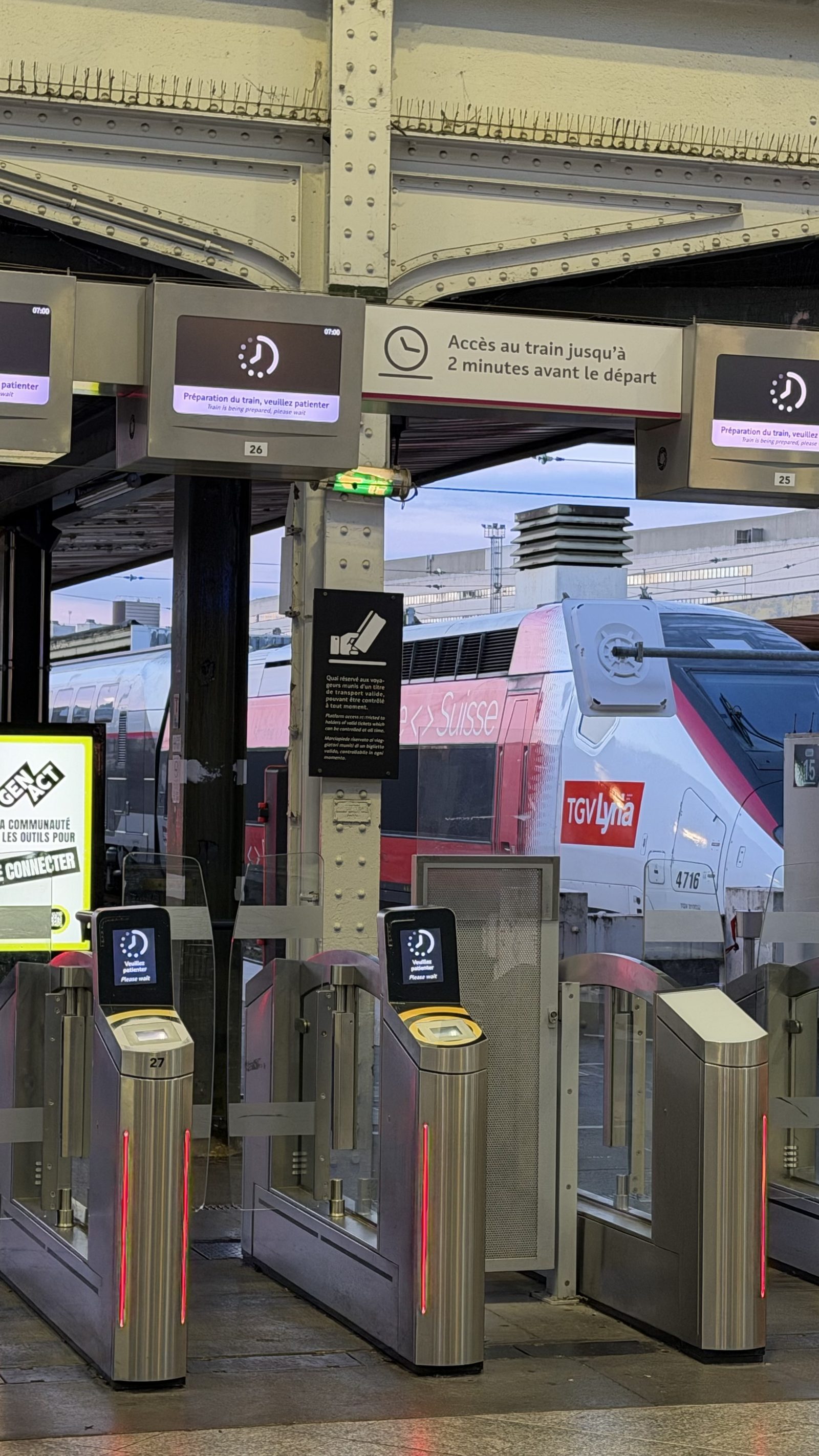 The platform gates at Gare de Lyon at seven in the morning, with the red and grey TGV waiting behind them