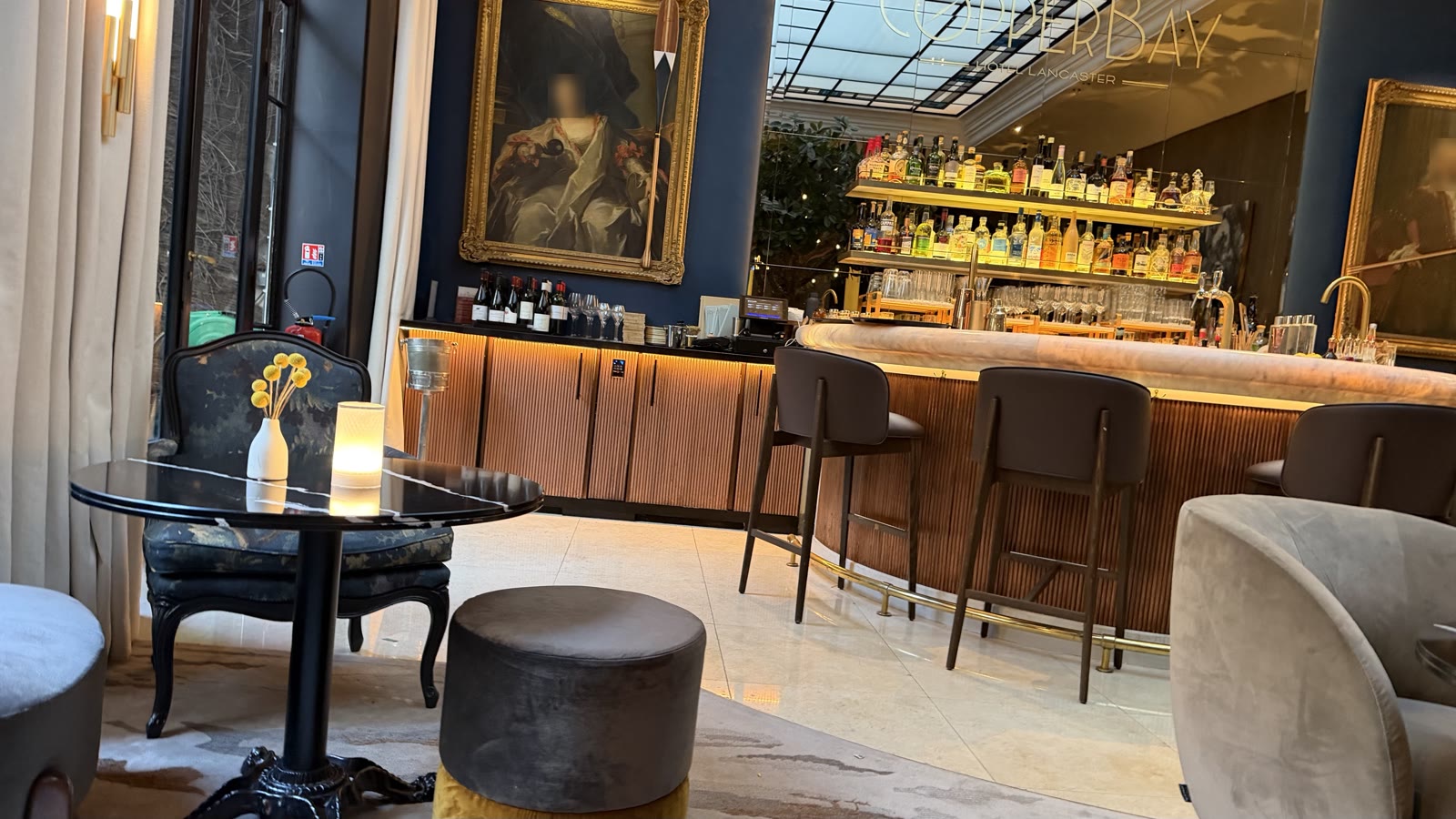 The bar seating area of the Hôtel Lancaster: velvet chairs, small round tables and a lit bar at the back