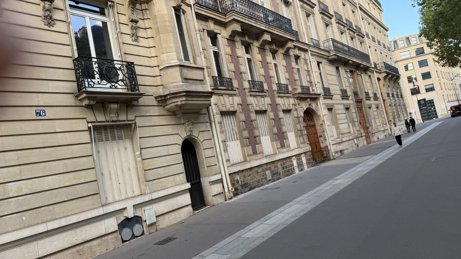 A quiet Haussmann-era street of the walk: pale stone facades, iron balconies and an empty road in evening light