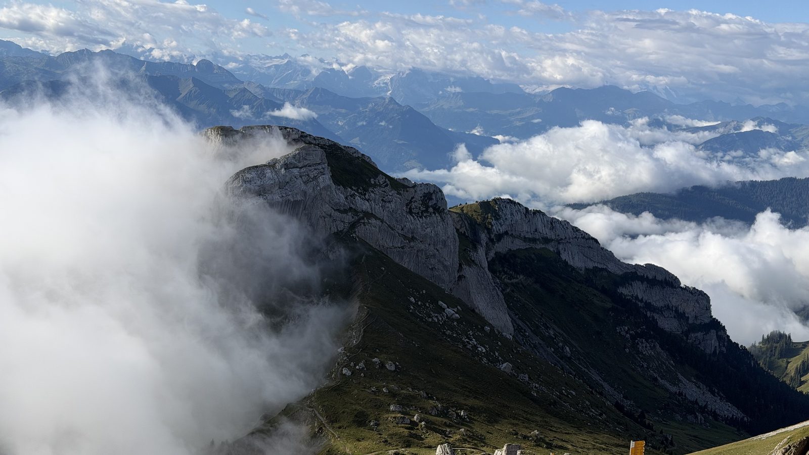 A rocky ridge on Pilatus standing above an unbroken sea of cloud with blue sky over it