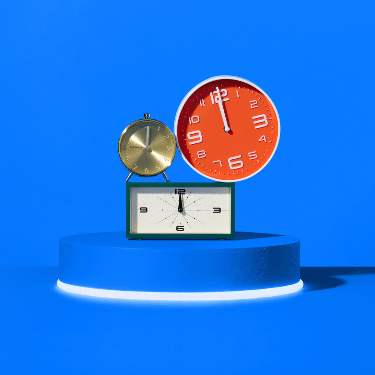 Three alarm clocks on a blue pedestal, all reading twelve, from Amazon's Prime Big Deal Days creator toolkit